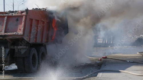 Firefighters extinguish a burning truck with water from the hose