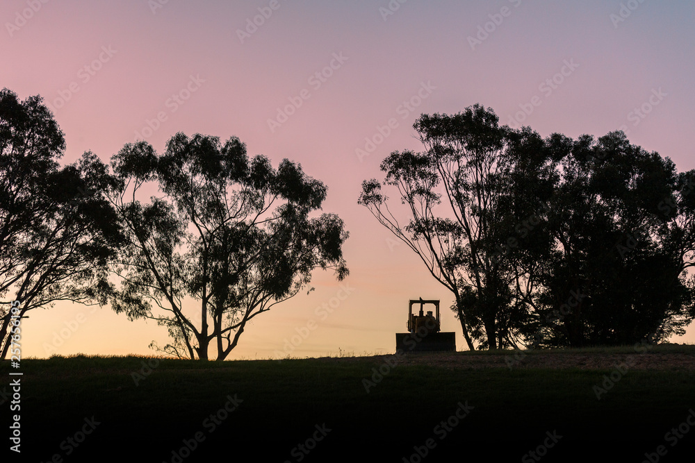 Silhouette agricultural farming machinery dusk landscape.