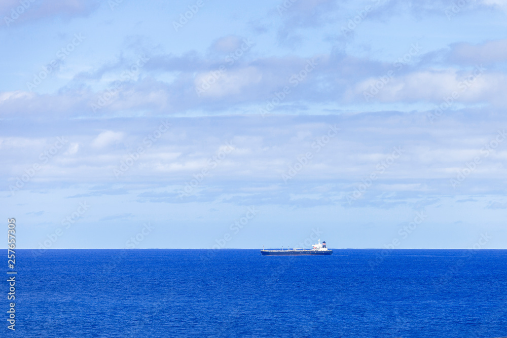 Industrial tanker sailing across ocean horizon.