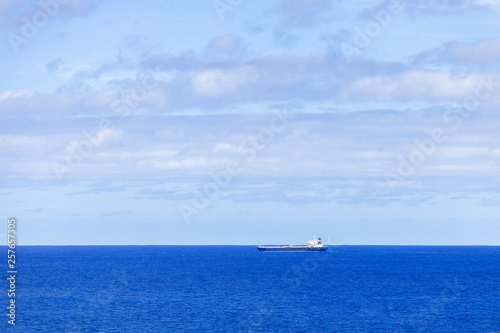 Industrial tanker sailing across ocean horizon.