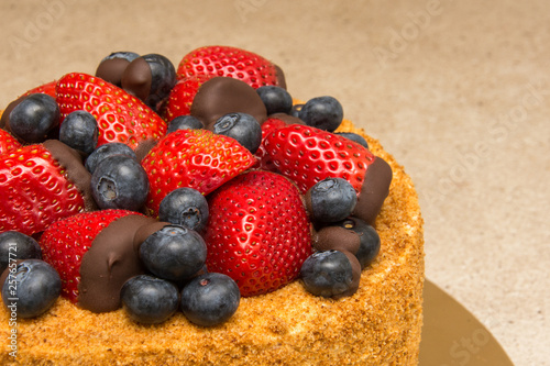 A home made honey cake with strawberries and blueberries on top
