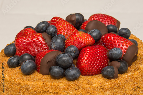 A home made honey cake with strawberries and blueberries on top