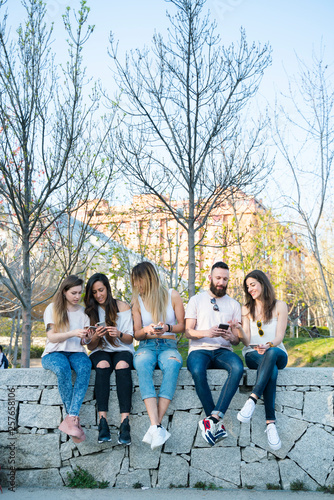 Group of five friends in the street with smartphone