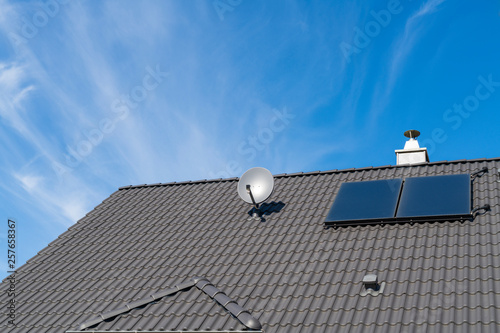 Ein Hausdach mit Satellitensch  ssel und kleiner Photovoltaikanlage