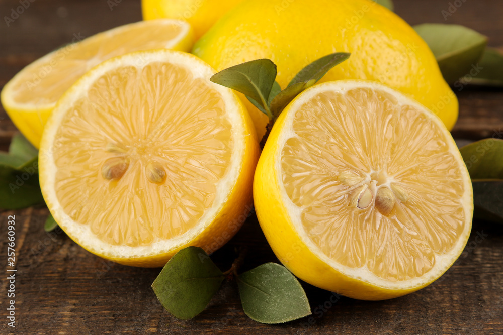Citrus fruit. Fresh lemon with leaves and lemon slices on a brown wooden table. close-up Citrus fruit. Fresh lemon with leaves and lemon slices on a brown wooden table. close-up