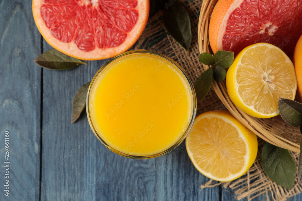 Citrus fruit. various citrus fruits with leaves of lemon, orange, grapefruit in a basket and orange juice on a blue wooden table. top view Citrus fruit. various citrus fruits with leaves of lemon, orange, grapefruit in a basket and orange juice on a blue wooden table. top view