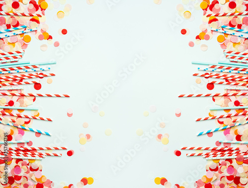Pile of red and blue straws on pastel background with colorful confetti. Festive background with copy space.