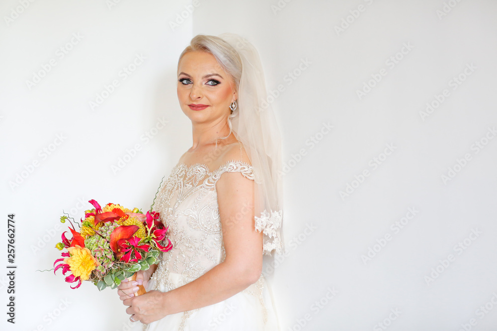 Beautiful blonde bride posing indoor with beautiful bouquet of flowers in hands Beautiful blonde bride posing indoor with beautiful bouquet of flowers in hands