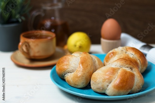 Rustic breakfast of fresh gluten free breadrolls, egg and a cup of tea with lemon