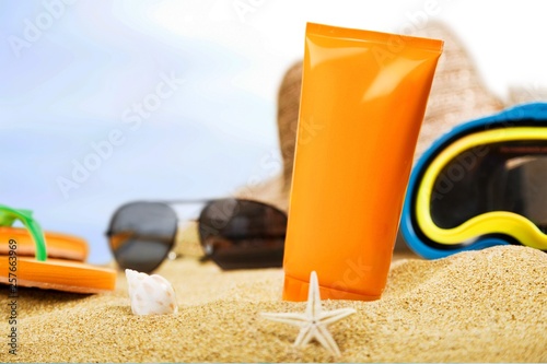 Bottle of sunscreen lotion on the sandy beach