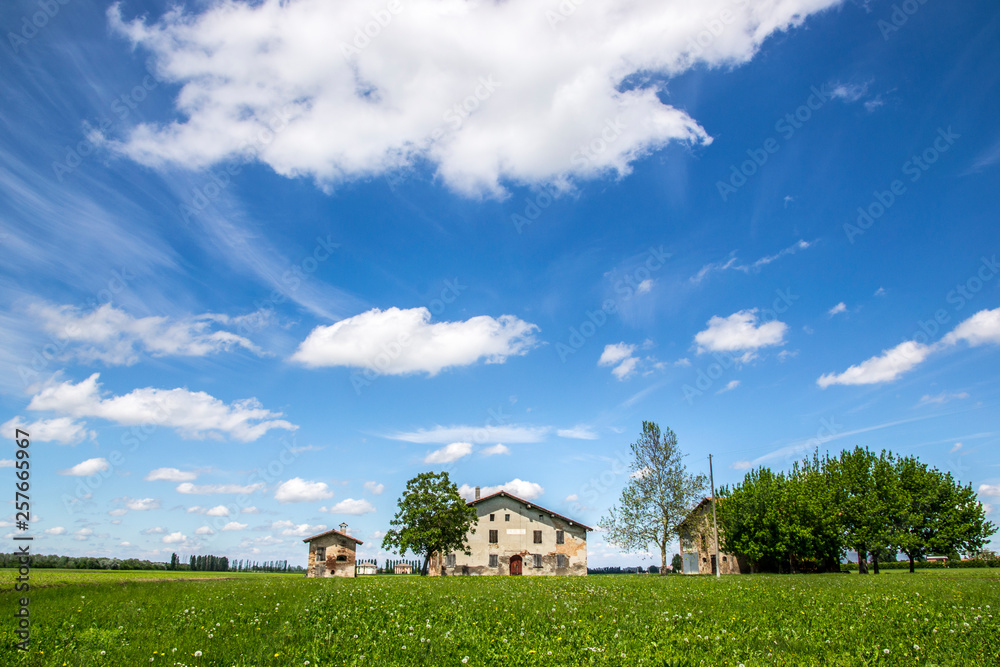 Paesaggio di campagna con cielo nuvoloso e casa rurale emiliana 