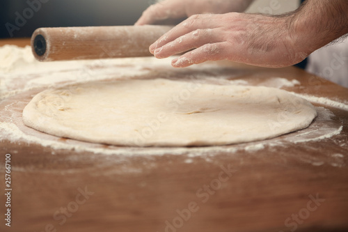  A man is cooking pizza. Closeup of male hands and dough.