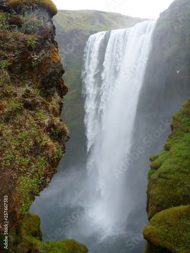 water cascade from Skogafoss Waterfall  Iceland viewed between two cliff rocks