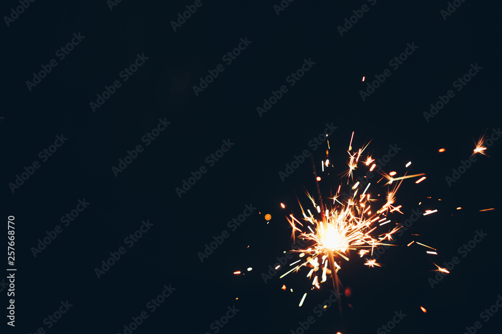sparkling Bengal sparklers sticks in flames on a black background with lights bokeh. christmas theme new year background. holiday card