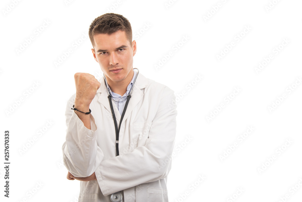 Portrait of young handsome doctor showing fist looking mad Portrait of young handsome doctor showing fist looking mad