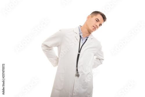 Portrait of young handsome doctor holding lower back like hurting