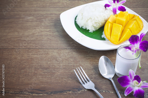Thai dessert  mango and sticky rice with coconut milk on a wooden background