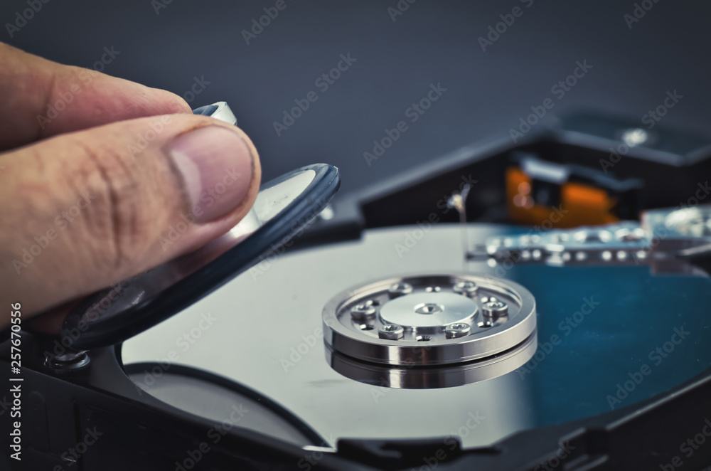 hand holding stethoscope for diagnose old dusty disassembled hard drive from the computer over dark background hand holding stethoscope for diagnose old dusty disassembled hard drive from the computer over dark background