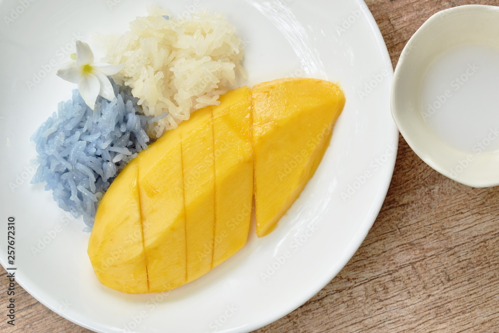 ripen mango with white and purple sticky rice dressing coconut milk on plate