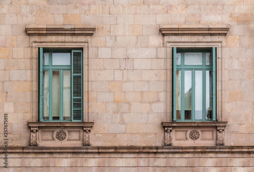 Two windows in a row on the facade of the urban historic building front view, Barcelona, Spain