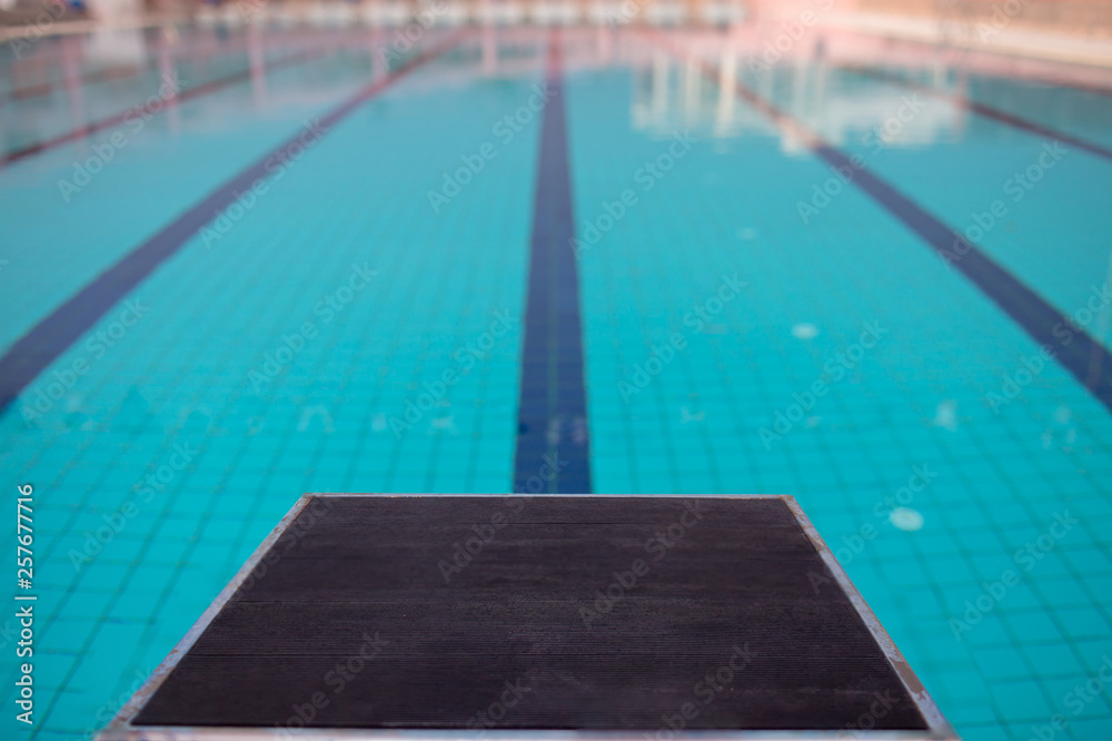 Starting blocks in row by the swimming pool, selective focus. Jump platform for swimming in swimming pool and grandstand background. Swimming pool with starting blocks. Sport facility. 