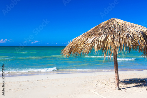 Fototapeta Naklejka Na Ścianę i Meble -  Straw umbrella on empty seaside beach in Varadero, Cuba. Relaxation, vacation idyllic background.