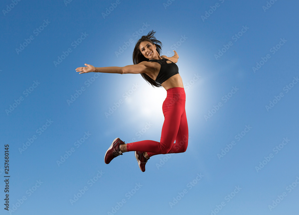 Fit woman jumping with blue sky background Fit woman jumping with blue sky background