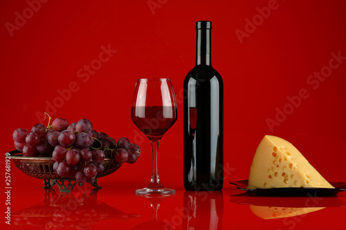 Fototapeta Naklejka Na Ścianę i Meble -  Red wine with cheese and grapes on red background