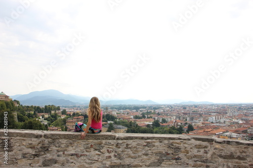 Giovane donna seduta sulle mura di Bergamo alta, porta San Giacomo. Lombardia, Italia photo