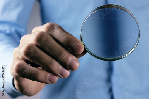 man holds magnifying glass in hand