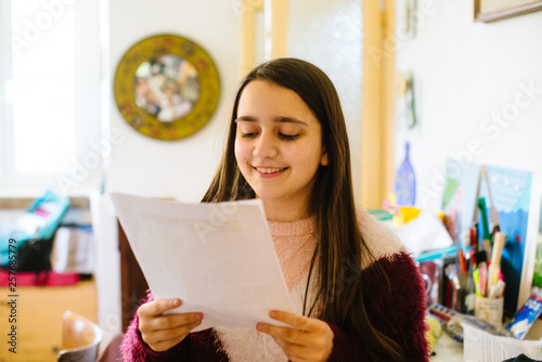 little girl, teen ager reads the papers she holds in her hand, studies for questioning school-close-up
