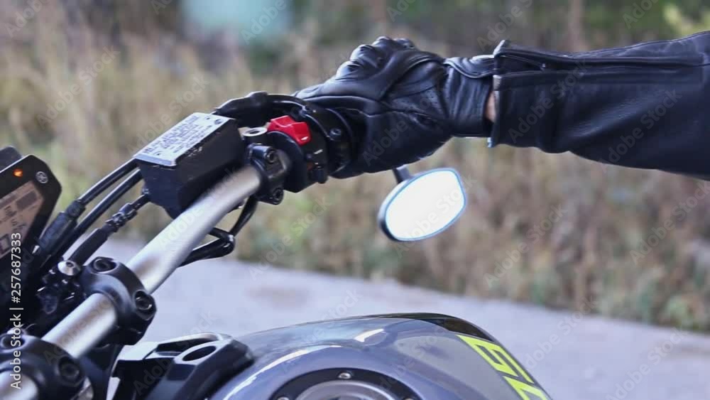 Closeup of a biker's hand. Biker twists the Handle of the Gas on the Wheel of the Motorcycle. A Biker start a motorcycle Closeup of a biker's hand. Biker twists the Handle of the Gas on the Wheel of the Motorcycle. A Biker start a motorcycle