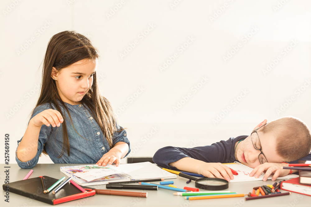 Little boy sleeping on desk with girl in background at classroom Little boy sleeping on desk with girl in background at classroom