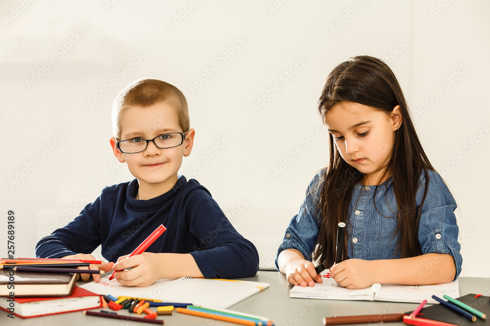 Portrait of two kids looking at workplace with schoolboys on background Portrait of two kids looking at workplace with schoolboys on background