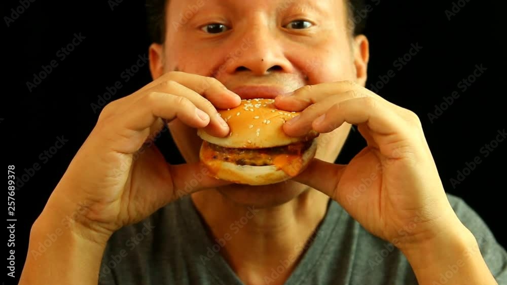 Thai man eating hamburger , in studio Chiangmai Thailand Thai man eating hamburger , in studio Chiangmai Thailand