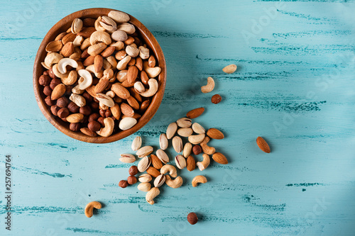 Assortment of nuts in wooden bowl on blue wooden table. Cashew, hazelnuts, almonds.