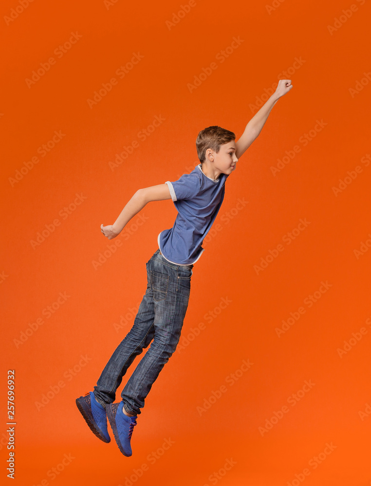 Fotografie Little boy jumping with raised fist like superhero