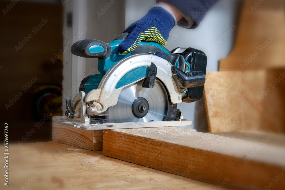 The joiner cuts a wooden board with an electric saw The joiner cuts a wooden board with an electric saw