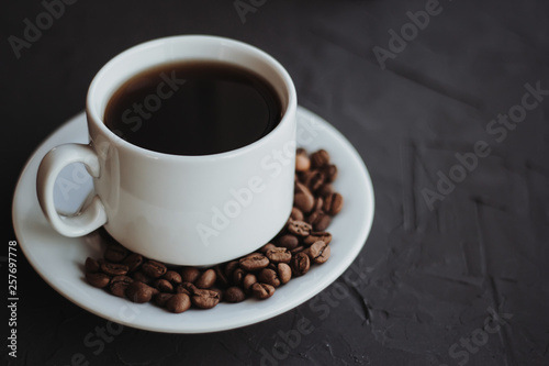 White cup of coffee and coffee beans on a dark background © Elena