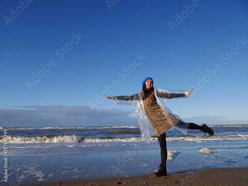 joyful girl depicts a flight on the beach. day. blue sea and waves. blue sky. The feeling of happiness and fun. horizontally. there is space for labels