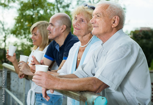 mature people with plastic cup standing in the park