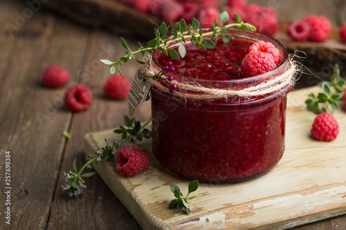 Raspberry jam in a glass jar and fresh raspberry and thyme photo