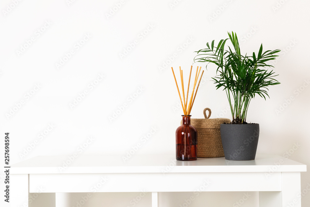 Scandinavian nordic hygge style, home interior - evergreen plant, scent aroma diffuser, small straw basket, white shelf