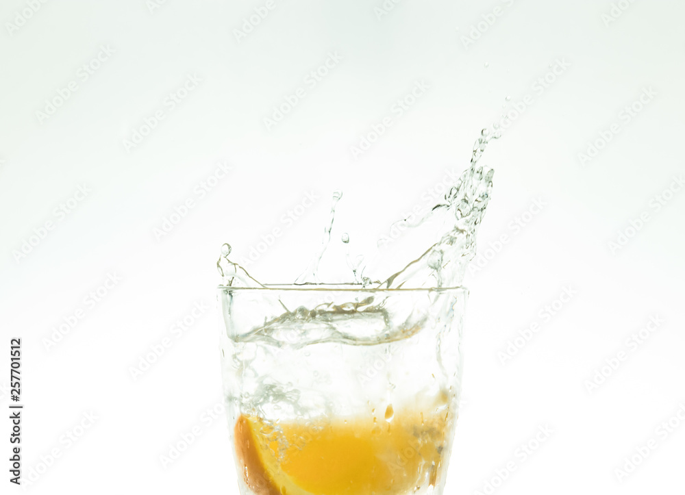 Slice the orange slice in a glass of water and make a spray on a white background. water spray in the air. a slice of citrus drops in a glass spray. Slice the orange slice in a glass of water and make a spray on a white background. water spray in the air. a slice of citrus drops in a glass spray.