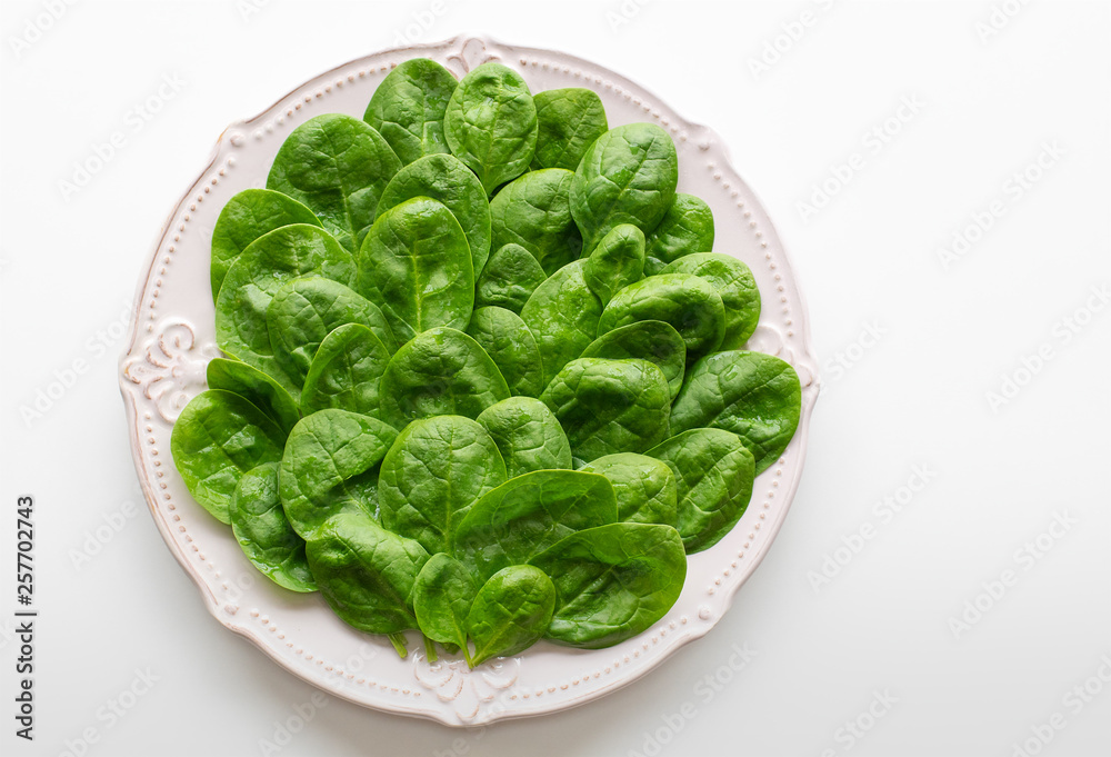 Young leaves of spinach on a plate. Copy space. Detox, a dietary food ingredient - green organic spinach. Young leaves of spinach on a plate. Copy space. Detox, a dietary food ingredient - green organic spinach.