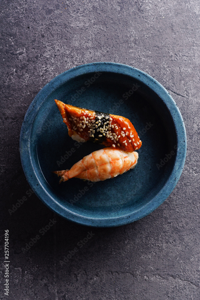 Overhead image of two sushi served on a plate. Shrimp and unagi on concrete background Overhead image of two sushi served on a plate. Shrimp and unagi on concrete background