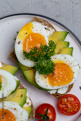Close up sandwich on grain bread with boiled egg and avocado on plate