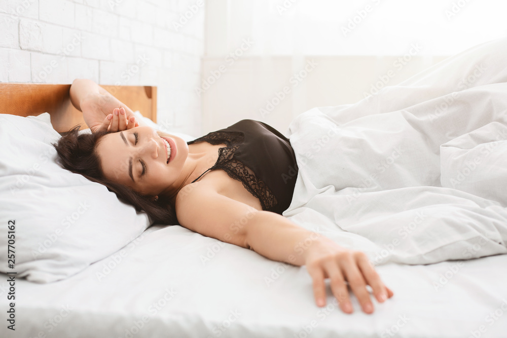 Smiling woman waking up in her bed - obrazy, fototapety, plakaty 