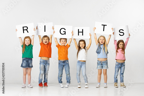 All people have rights. Group of happy smiling and screaming children with a white banners making word isolated in studio background. Education, advertising and social right concept. photo