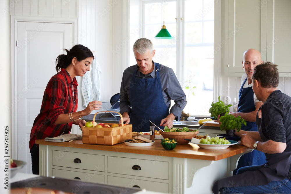 Mature friends preparing food together in kitchen at home Mature friends preparing food together in kitchen at home